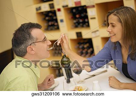 Close-up of a mid adult woman feeding a mid adult man View Large Photo Image Stock Photograph - Close-up of a mid adult woman feeding a mid adult man. Fotosearch