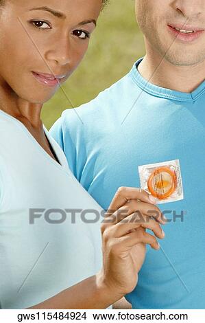 Close-up of a mid adult woman holding a condom with a man behind him View Large Photo Image Picture - Close-up of a mid adult woman holding a condom with a man behind him. Fotosearch