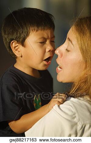 Stock Image - Close-up of a mid adult woman holding her son. Fotosearch