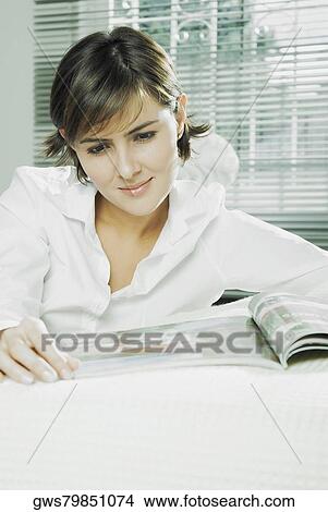 Close-up of a mid adult woman reading a magazine View Large Photo Image Picture - Close-up of a mid adult woman reading a magazine. Fotosearch