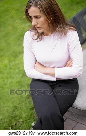 Stock Photo - Close-up of a mid adult woman sitting on a bench. Fotosearch
