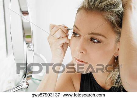 Close-up of a mid adult woman tweezing her eyebrows View Large Photo Image Stock Photo - Close-up of a mid adult woman tweezing her eyebrows. Fotosearch