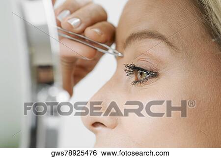 Close-up of a mid adult woman tweezing her eyebrows View Large Photo Image Stock Photograph - Close-up of a mid adult woman tweezing her eyebrows. Fotosearch
