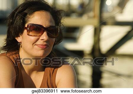 Close-up of a mid adult woman wearing sunglasses and smiling View Large Photo Image Stock Image - Close-up of a mid adult woman wearing sunglasses and smiling. Fotosearch