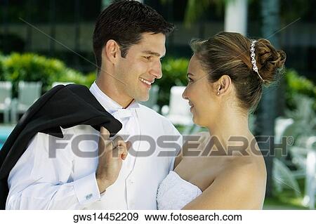 Close-up of a newlywed couple facing each other and smiling View Large Photo Image Stock Photo - Close-up of a newlywed couple facing each other and smiling. Fotosearch