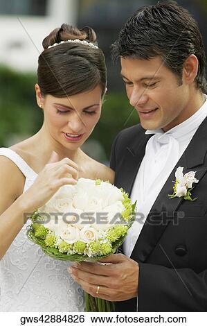 Close-up of a newlywed couple looking at a bouquet of flowers View Large Photo Image Stock Photograph - Close-up of a newlywed couple looking at a bouquet of flowers. Fotosearch