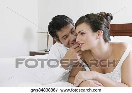 Close-up of a newlywed couple lying on the bed and smiling View Large Photo Image Stock Photo - Close-up of a newlywed couple lying on the bed and smiling. Fotosearch