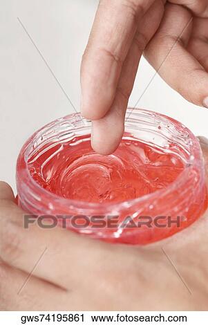 Stock Image - Close-up of a person holding a bottle of gel. Fotosearch