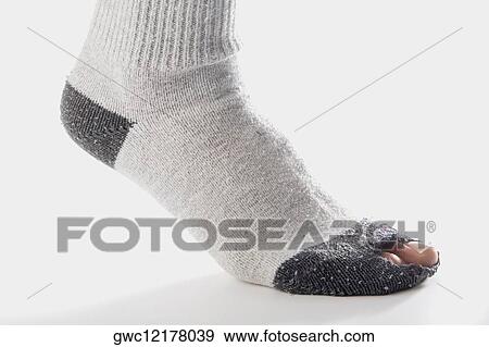 Stock Photo - Close-up of a person wearing torn socks. Fotosearch
