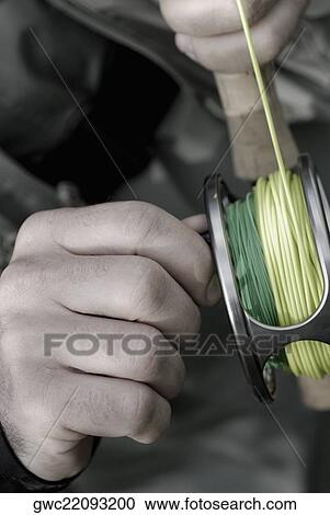 Stock Image - Close-up of a person's hand holding a fishing reel. Fotosearch