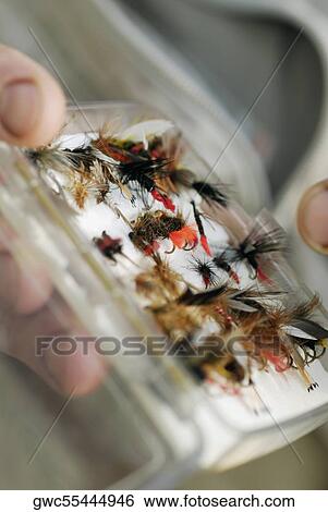 Stock Photograph - Close-up of a person's hand holding a box of flies and lures. Fotosearch