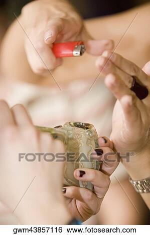 Stock Photograph - Close-up of a person's hands lighting a smoke pipe. Fotosearch