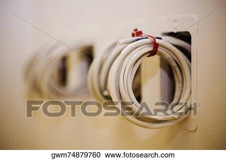 Stock Image - Close-up of a roll of cables coming out from a wall. Fotosearch