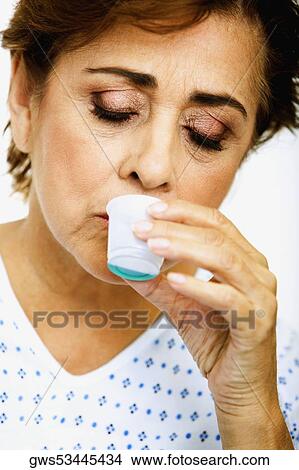 Close-up of a senior woman taking medicine from a measuring cup View Large Photo Image Picture - Close-up of a senior woman taking medicine from a measuring cup. Fotosearch