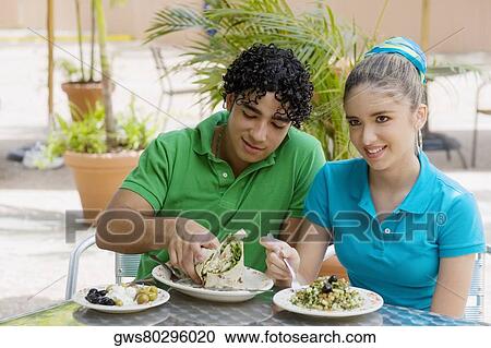Close-up of a teenage girl and a young man eating salad and a wrap in a restaurant View Large Photo Image Stock Image - Close-up of a teenage girl and a young man eating salad and a wrap in a restaurant. Fotosearch