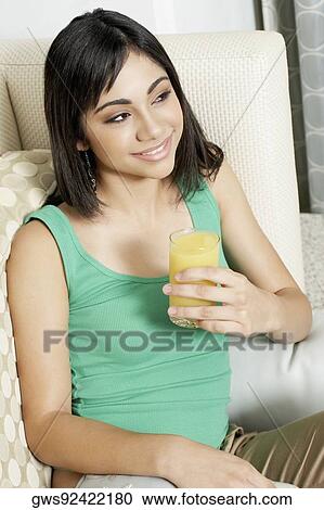Stock Image - Close-up of a teenage girl holding a glass of orange juice. Fotosearch