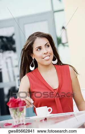 Stock Image - Close-up of a teenage girl stirring tea with a teaspoon and smiling. Fotosearch