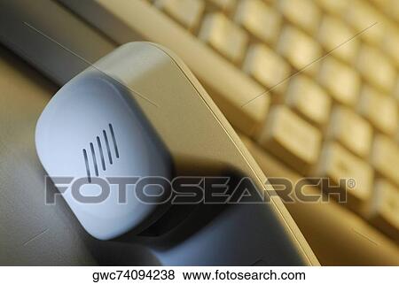 Close-up of a telephone receiver in front of a computer keyboard View Large Photo Image Stock Photo - Close-up of a telephone receiver in front of a computer keyboard. Fotosearch