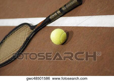Stock Photograph - Close-up of a tennis ball with a tennis racket on a tennis court. Fotosearch
