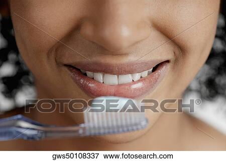 Close-up of a toothbrush with toothpaste in front of a young woman's mouth View Large Photo Image Stock Photo - Close-up of a toothbrush with toothpaste in front of a young woman's mouth. Fotosearch