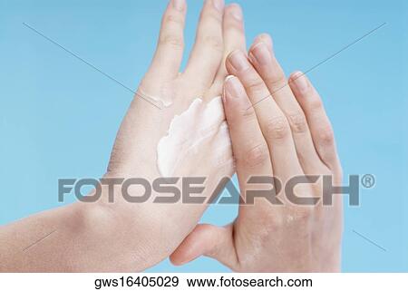 Stock Photo - Close-up of a woman's hand applying moisturizer. Fotosearch
