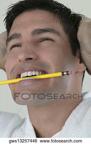Close-up of a young man biting a pencil with his head in his hands View Large Photo Image Stock Photograph - Close-up of a young man biting a pencil with his head in his hands. Fotosearch