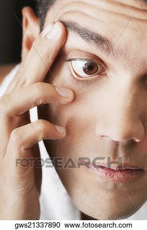Stock Image - Close-up of a young man checking his eye. Fotosearch