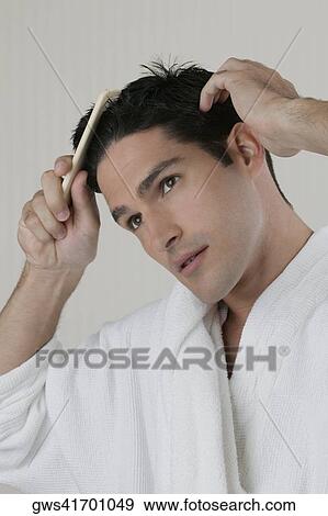 Close-up of a young man combing his hair View Large Photo Image Stock Photo - Close-up of a young man combing his hair. Fotosearch