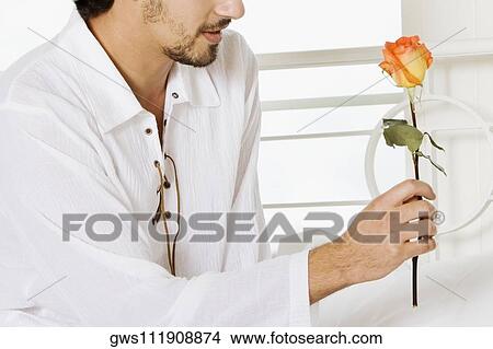 Close-up of a young man holding a rose View Large Photo Image Picture - Close-up of a young man holding a rose. Fotosearch