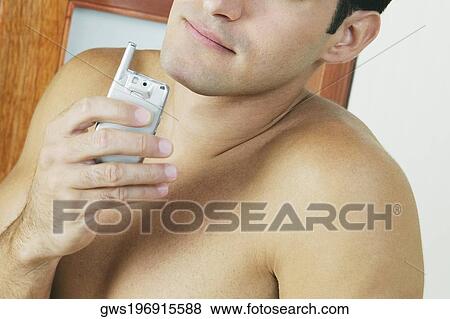 Close-up of a young man holding a mobile phone View Large Photo Image Stock Photo - Close-up of a young man holding a mobile phone. Fotosearch