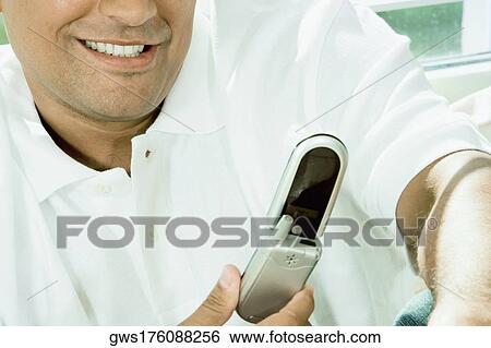 Close-up of a young man holding a mobile phone View Large Photo Image Stock Photograph - Close-up of a young man holding a mobile phone. Fotosearch