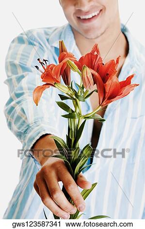 Close-up of a young man holding flowers and smiling View Large Photo Image Stock Image - Close-up of a young man holding flowers and smiling. Fotosearch