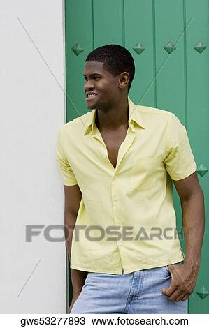 Close-up of a young man leaning against a wall and smiling View Large Photo Image Stock Image - Close-up of a young man leaning against a wall and smiling. Fotosearch