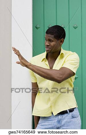 Close-up of a young man leaning against a wall and gesturing View Large Photo Image Stock Photo - Close-up of a young man leaning against a wall and gesturing. Fotosearch