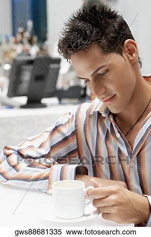 Stock Photography - Close-up of a young man looking at a coffee cup. Fotosearch