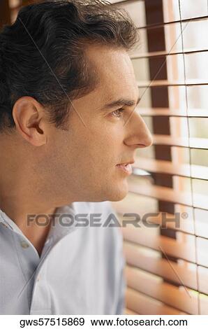Close-up of a young man looking out of a window View Large Photo Image Stock Photo - Close-up of a young man looking out of a window. Fotosearch