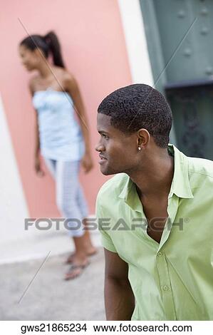 Close-up of a young man looking sideways with a teenage girl standing behind him View Large Photo Image Picture - Close-up of a young man looking sideways with a teenage girl standing behind him. Fotosearch