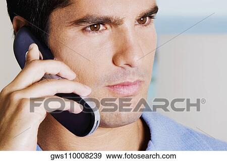 Close-up of a young man talking on a mobile phone View Large Photo Image Stock Photo - Close-up of a young man talking on a mobile phone. Fotosearch