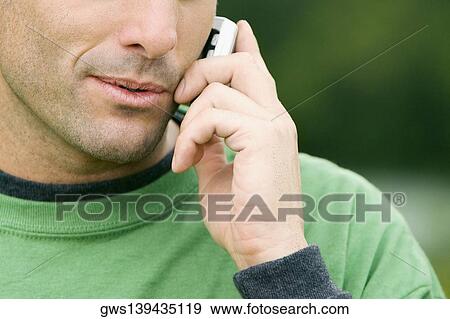 Close-up of a young man talking on a mobile phone View Large Photo Image Stock Photo - Close-up of a young man talking on a mobile phone. Fotosearch