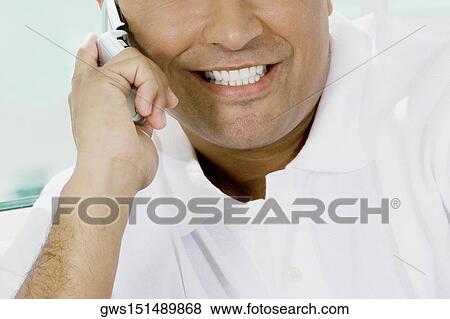 Stock Photo - Close-up of a young man talking on a mobile phone and smiling. Fotosearch