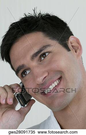 Stock Photography - Close-up of a young man talking on a mobile phone. Fotosearch