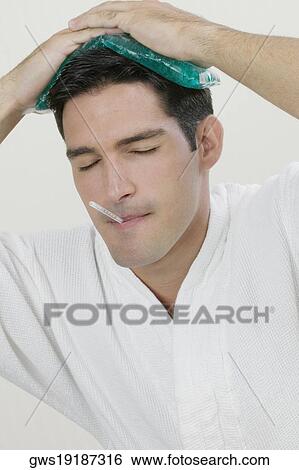 Close-up of a young man with an ice pack on his head and a thermometer in his mouth View Large Photo Image Stock Photograph - Close-up of a young man with an ice pack on his head and a thermometer in his mouth. Fotosearch
