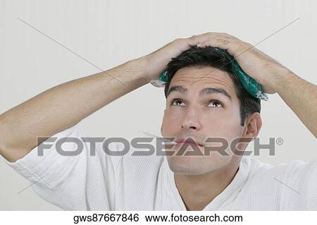Close-up of a young man with an ice pack on his head and a thermometer in his mouth View Large Photo Image Stock Photograph - Close-up of a young man with an ice pack on his head and a thermometer in his mouth. Fotosearch
