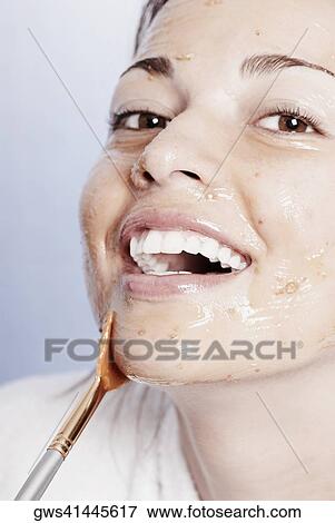 Stock Photo - Close-up of a young woman applying a facial mask. Fotosearch