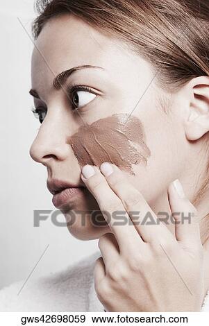 Close-up of a young woman applying a facial mask View Large Photo Image Stock Photo - Close-up of a young woman applying a facial mask. Fotosearch