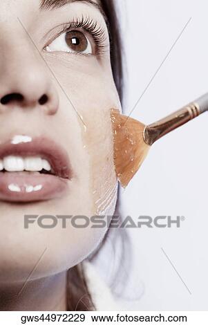 Close-up of a young woman applying a facial mask View Large Photo Image Stock Photo - Close-up of a young woman applying a facial mask. Fotosearch