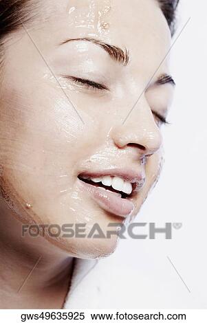 Stock Photography - Close-up of a young woman applying a facial mask. Fotosearch
