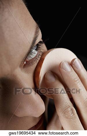 Close-up of a young woman applying face powder with a powder puff View Large Photo Image Picture - Close-up of a young woman applying face powder with a powder puff. Fotosearch