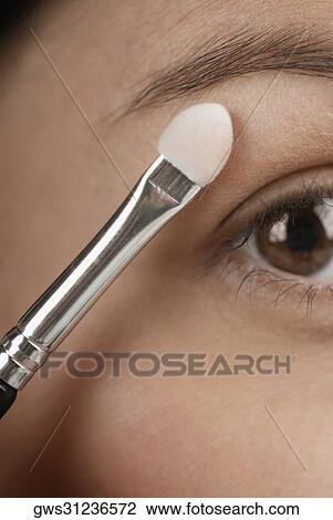 Close-up of a young woman applying eyeshadow View Large Photo Image Stock Image - Close-up of a young woman applying eyeshadow. Fotosearch
