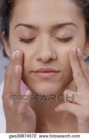 Close-up of a young woman applying moisturizer on her cheeks View Large Photo Image Stock Image - Close-up of a young woman applying moisturizer on her cheeks. Fotosearch